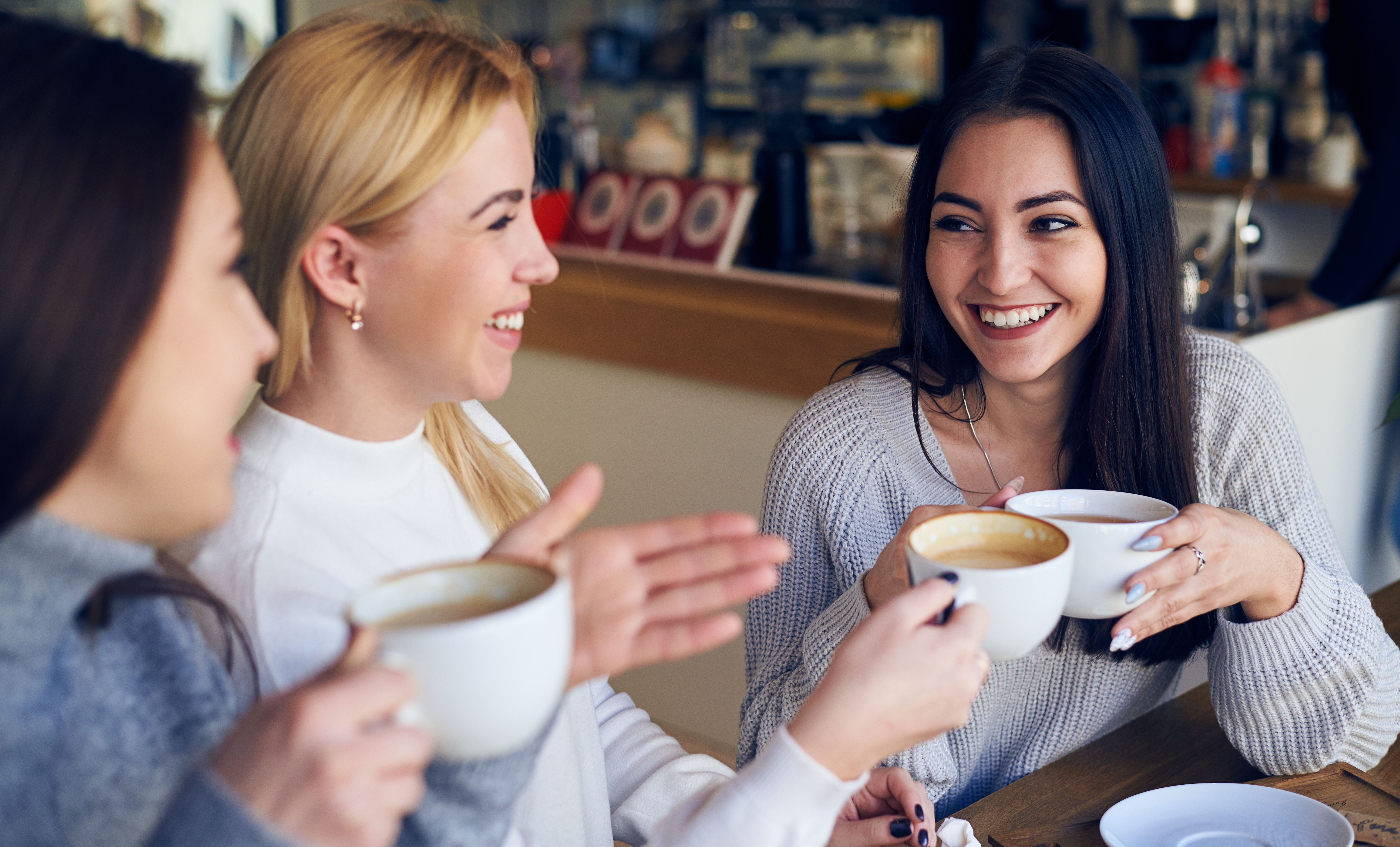 Friends smiling and talking over coffee at a café